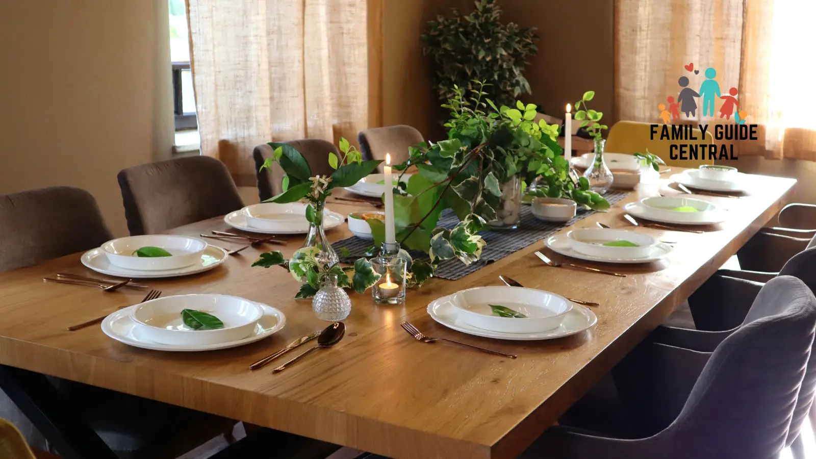 Big brown dining table with white plates and center plant piece - familyguidecentral.com